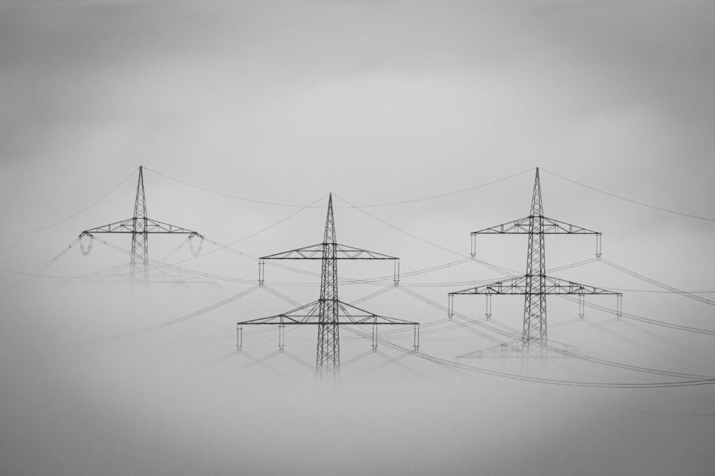 Eerie monochrome view of power lines emerging through dense fog.